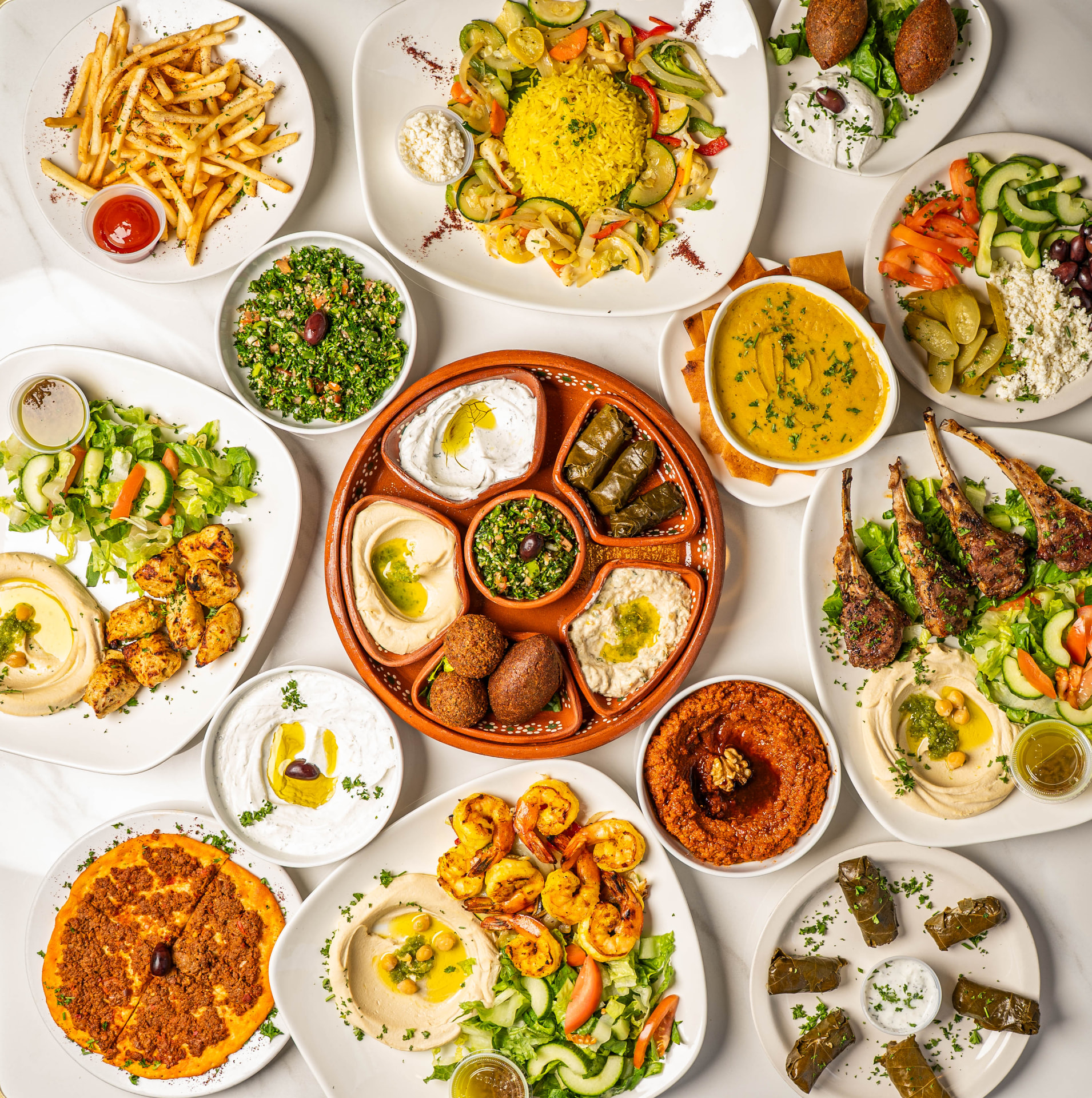 Overhead spread of mezze, kebabs, tabbouleh and lamb chops