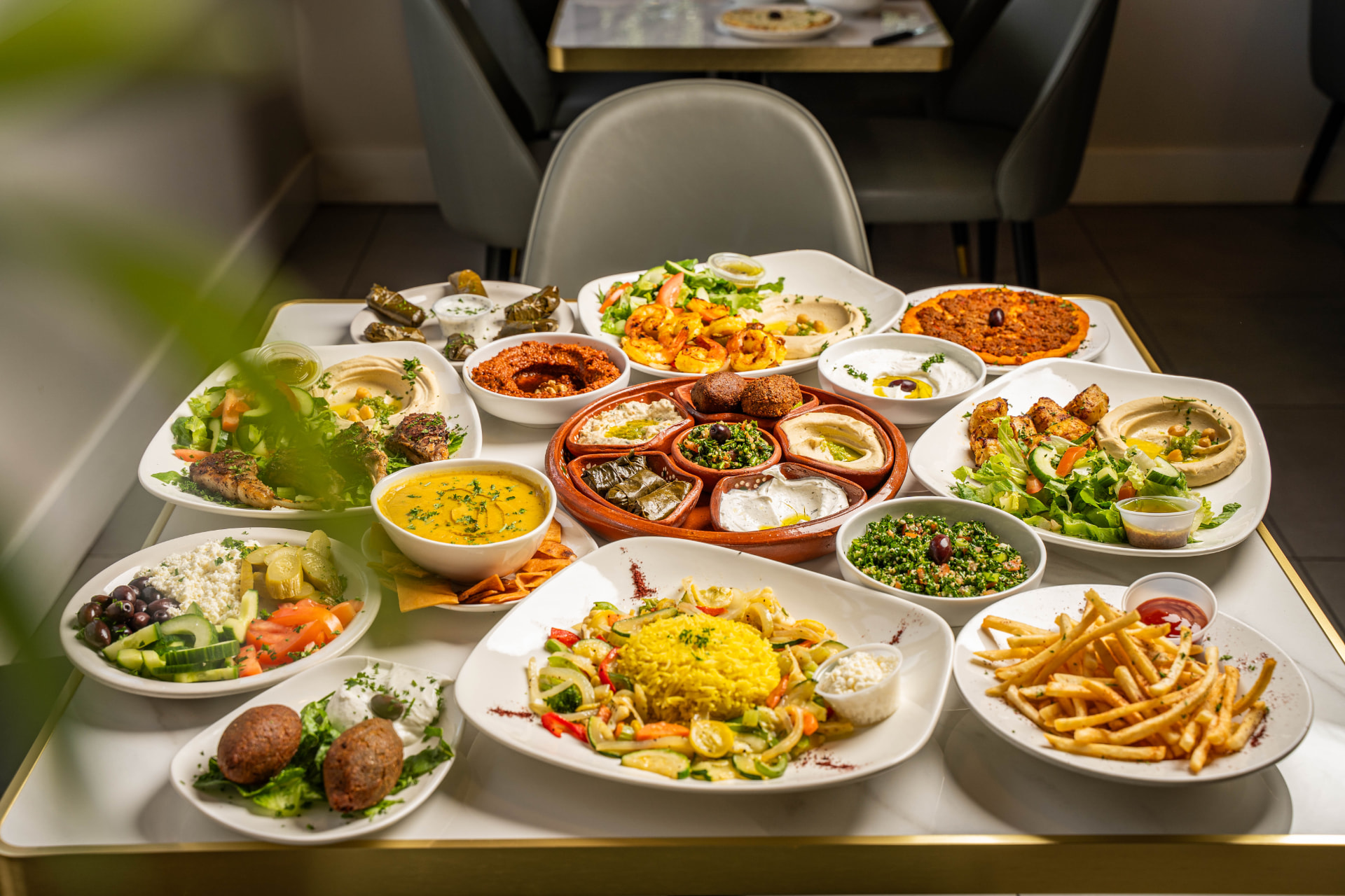 A full table of Mona's Cafe mezze, salads, kebabs and fresh pita